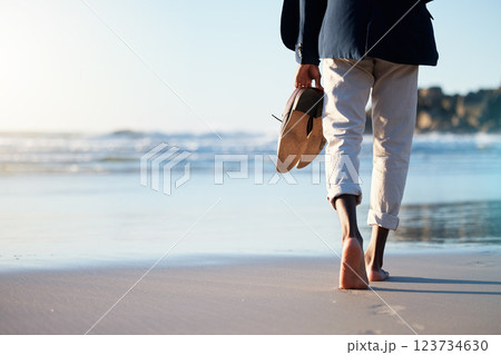 Walking, beach and mental heath with a business man walking in the sand by the sea or ocean after work. Water, nature and freedom with a male employee taking a walk on the coast during summer 123734630