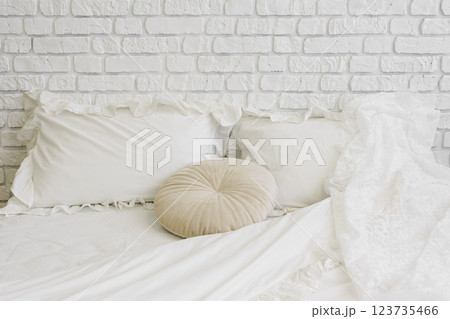 Cozy and inviting white bedding, stylish minimalist bed with pillows in white brick wall background 123735466