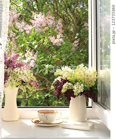 Still life with blooming lilac flowers in a vase and a cup of tea on a sunny window, abstract floral arrangement, Home interior with decor elements, floral birthday card, wedding, Still life with blooming lilac flowers in a vase and a cup of tea on a sunny window, abstract floral arrangement, Home interior with decor elements, floral birthday card, wedding, 123735860