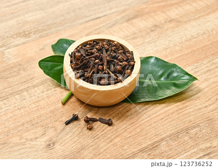 Dried herb, dried cloves in wood bowl  on wood table. 123736252