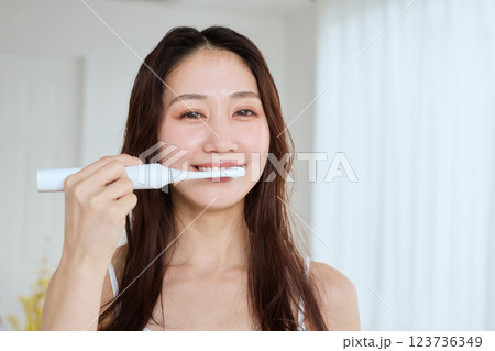 電動歯ブラシで歯を磨く女性 123736349