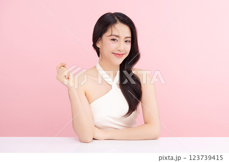 A beautiful young Asian woman with clean, fresh skin against a pink background. Skincare, facial treatment, cosmetology, beauty, and spa. An elegant portrait of an Asian woman. 123739415