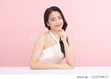 A beautiful young Asian woman with clean, fresh skin against a pink background. Skincare, facial treatment, cosmetology, beauty, and spa. An elegant portrait of an Asian woman. 123739417