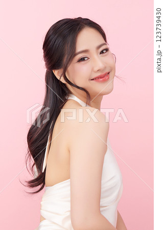 A beautiful young Asian woman with clean, fresh skin against a pink background. Skincare, facial treatment, cosmetology, beauty, and spa. An elegant portrait of an Asian woman. 123739430