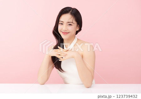 A beautiful young Asian woman with clean, fresh skin against a pink background. Skincare, facial treatment, cosmetology, beauty, and spa. An elegant portrait of an Asian woman. 123739432