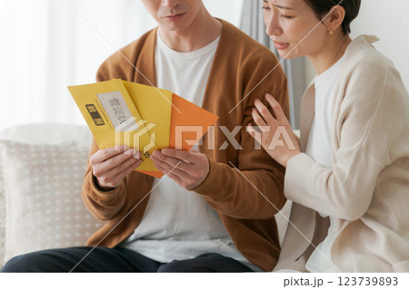 督促状の封筒を見て困る夫婦 督促状の封筒を見て困る夫婦 123739893