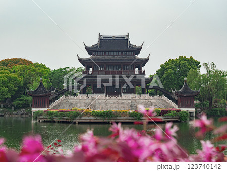 A stunning pavilion showcases classic Chinese architecture, surrounded by lush greenery and vibrant pink flowers A stunning pavilion showcases classic Chinese architecture, surrounded by lush greenery and vibrant pink flowers 123740142