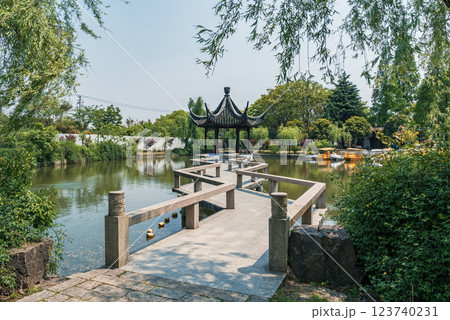 Serene view of a traditional pavilion beside a tranquil lake surrounded by lush greenery 123740231