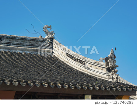 Traditional Asian architectural rooftop with intricate dragon ornamentation under clear blue sky Traditional Asian architectural rooftop with intricate dragon ornamentation under clear blue sky 123740285