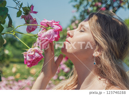 Young woman enjoys a sunny day among blooming roses in a vibrant garden setting 123740288