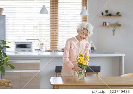 自宅のダイニングテーブルに花を飾るシニア女性 自宅のダイニングテーブルに花を飾るシニア女性 123740488