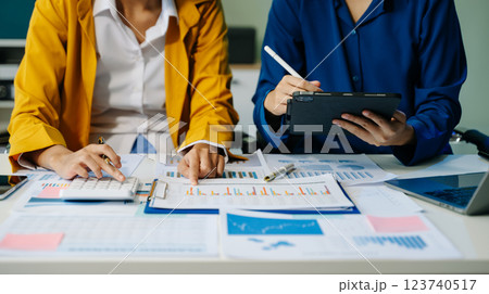 Business documents on office table with smart phone and laptop and two colleagues discussing data 123740517
