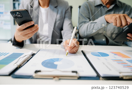 Business documents on office table with smart phone and laptop and two colleagues discussing data 123740529