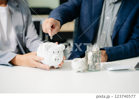 business team  holding coins putting in glass with using smartphone and calculator 123740577