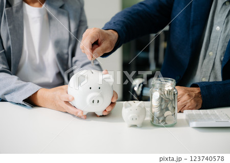 business team  holding coins putting in glass with using smartphone and calculator 123740578