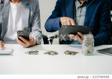 business team  holding coins putting in glass with using smartphone and calculator 123740580