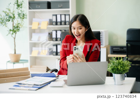 Beautiful woman typing on tablet and laptop while sitting at the working white table 123740834