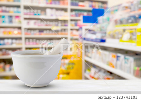 Mortar and pestle on pharmacy counter top with blur medicine shelves in drugstore background Mortar and pestle on pharmacy counter top with blur medicine shelves in drugstore background 123741103