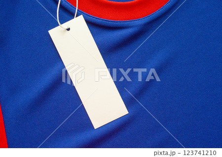 Blank white clothes tag label on blue fabric texture background 123741210