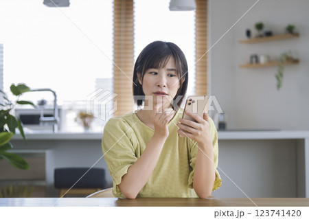困った顔でスマホを見つめるアラサーの女性 困った顔でスマホを見つめるアラサーの女性 123741420