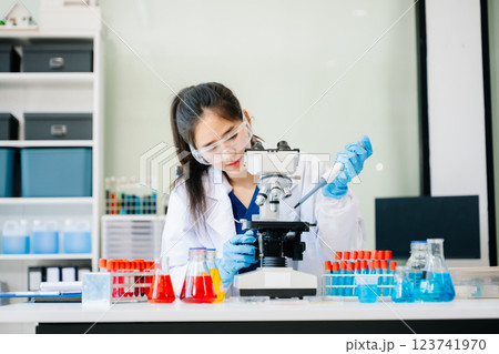 female scientist working with micro pipettes analyzing biochemical female scientist working with micro pipettes analyzing biochemical 123741970
