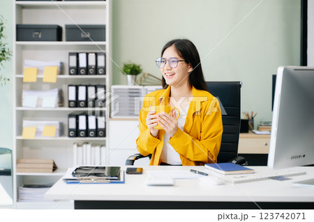 Young Asian businesswoman working with working notepad, tablet and laptop documents talking 123742071