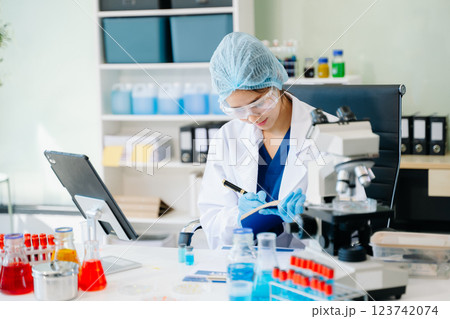 female scientist working with micro pipettes analyzing biochemical 123742074