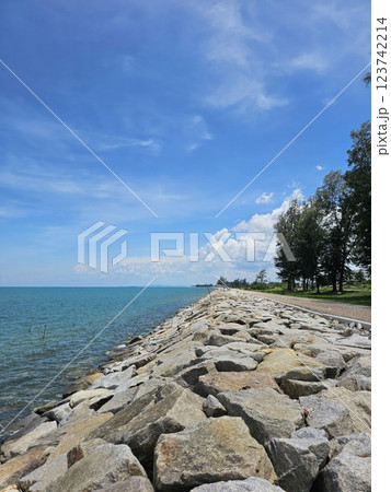 Serene Rocky Shoreline Against Clear Blue Sky and Calm Waters Serene Rocky Shoreline Against Clear Blue Sky and Calm Waters 123742214