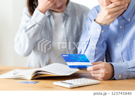 家で家計簿をつけながら悩むミドル夫婦 123743840