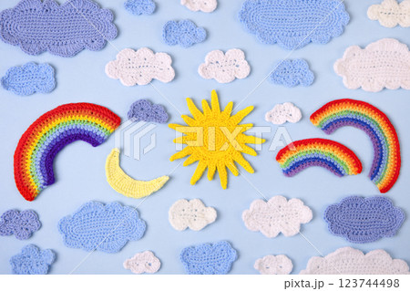 Knitted toys blue and white clouds, yellow sun, rainbow, moon on blue background. Baby stuff and accessories. Top view, flat lay, banner Knitted toys blue and white clouds, yellow sun, rainbow, moon on blue background. Baby stuff and accessories. Top view, flat lay, banner 123744498