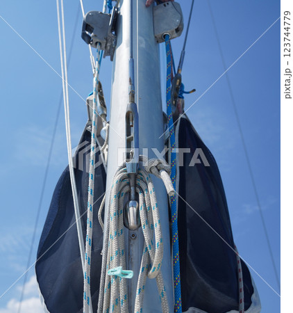 Tall sturdy mast of a sailboat stands out vividly against the bright blue sky. 123744779