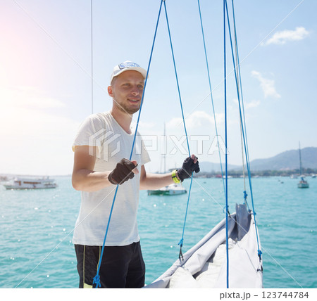 Male captain on deck of sailboat unpacking sails pulling zipper Male captain on deck of sailboat unpacking sails pulling zipper 123744784