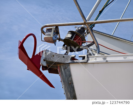 A bright red anchor is securely attached to the side of a sailing boat 123744790