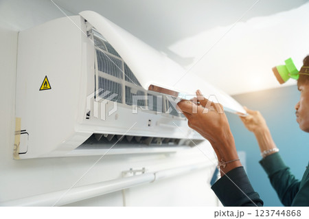 The worker cleans and repairs the air conditioner to ensure it operates properly The worker cleans and repairs the air conditioner to ensure it operates properly 123744868