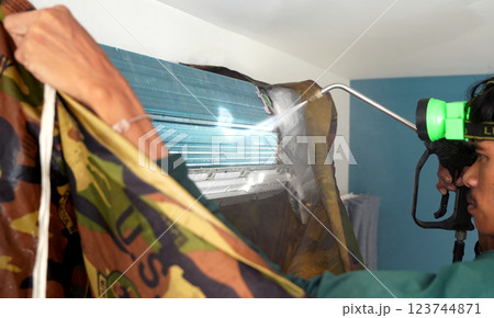 The worker cleans and repairs the air conditioner to ensure it operates properly 123744871