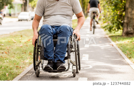 Handicapped man in wheelchair walk at the park alley Handicapped man in wheelchair walk at the park alley 123744882