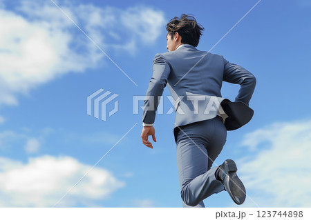 青空に向かって走るスーツ姿の若い男性ビジネスマン 123744898