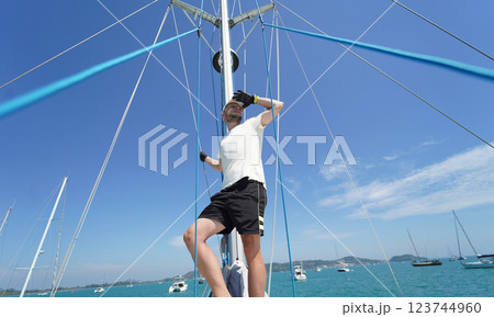 Male captain stands proudly on a sailboat enjoying the moment 123744960
