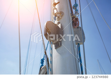 Tall sturdy mast of a sailboat stands out vividly against the bright blue sky. 123744980