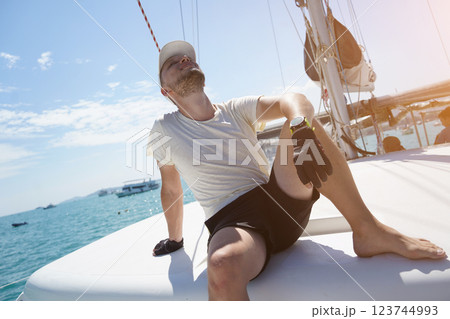 A man is calmly sitting on the deck of a beautiful sailboat 123744993