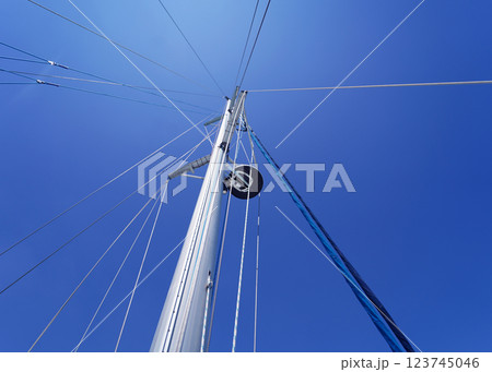 Tall sturdy mast of a sailboat stands out vividly against the bright blue sky. 123745046