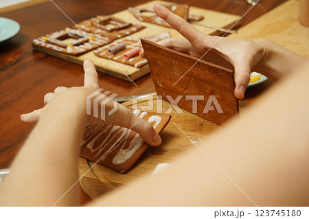 Mother and daughter at the table cooking gingerbread house for Christmas 123745180