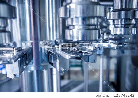 Automatic filling machine pours water into plastic PET bottles. 123745242