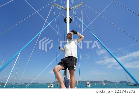 Male captain stands proudly on a sailboat enjoying the moment Male captain stands proudly on a sailboat enjoying the moment 123745272