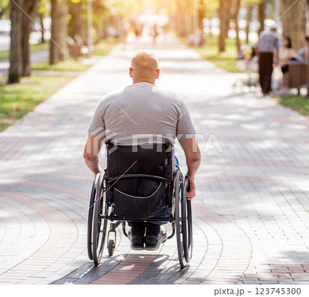 Handicapped man in wheelchair walk at the park alley Handicapped man in wheelchair walk at the park alley 123745300