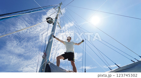 Male captain stands proudly on a sailboat enjoying the moment Male captain stands proudly on a sailboat enjoying the moment 123745302