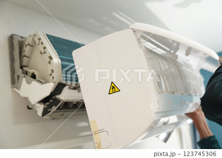 The worker cleans and repairs the air conditioner to ensure it operates properly 123745306