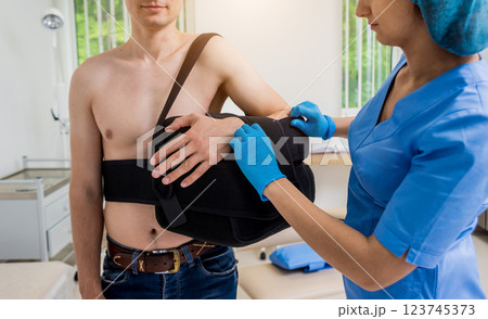 Nurse putting a sling on patients arm that is broken. Injury Nurse putting a sling on patients arm that is broken. Injury 123745373
