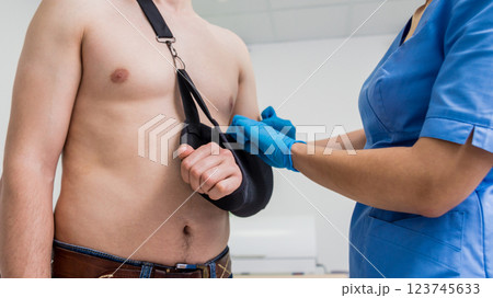 Nurse putting a sling on patients arm that is broken. Injury Nurse putting a sling on patients arm that is broken. Injury 123745633