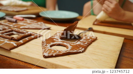 Mother and daughter at the table cooking gingerbread house for Christmas 123745712